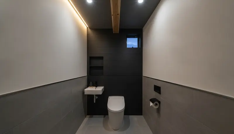 戸建て(広め)のトイレをスタイリッシュに。グレーの大判タイルの壁一面が主役。